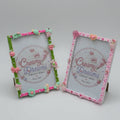Two decorative picture frames displayed on a pink patterned backdrop. The top frame has a green border with pink, peach, and mint embellishments, and the bottom frame has a pink border with similar decorative details.